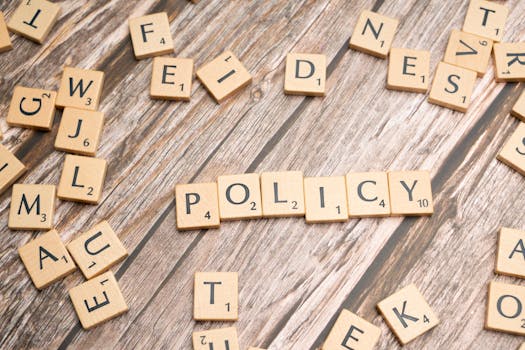 Scrabble letter tiles on a wooden background forming the word "Policy".